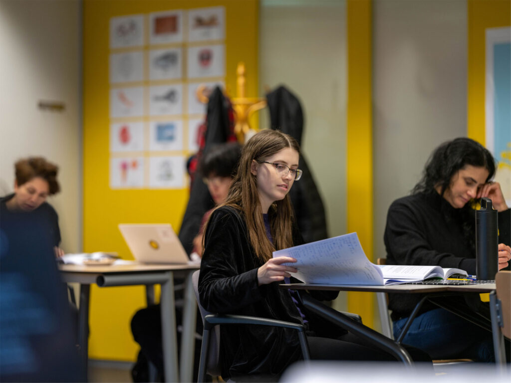 Studenten werken geconcentreerd aan hun opdrachten tijdens de Engelse les op A2-niveau.