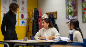 Interactief moment tussen cursisten en docent in een kleurrijk klaslokaal met leerposters aan de muur.