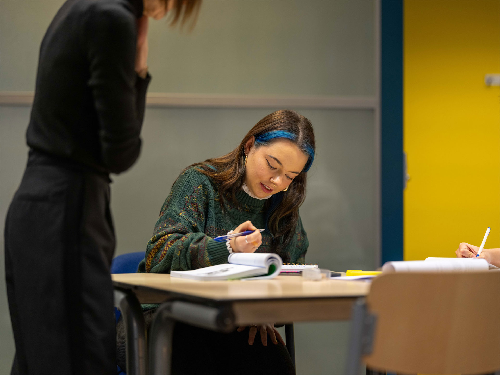 Een cursist in gesprek met een docent tijdens een taalles Nederlands, met focus op spreekvaardigheid in een ontspannen sfeer.